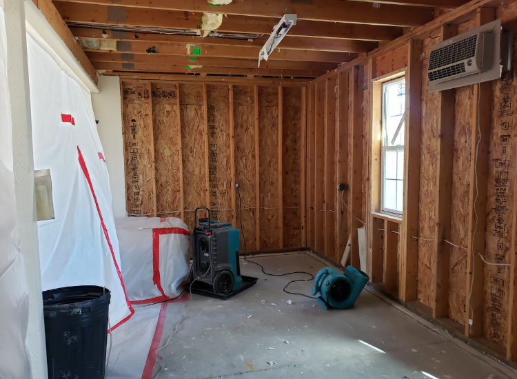 Dehumidifier and fan in an unfinished room.
