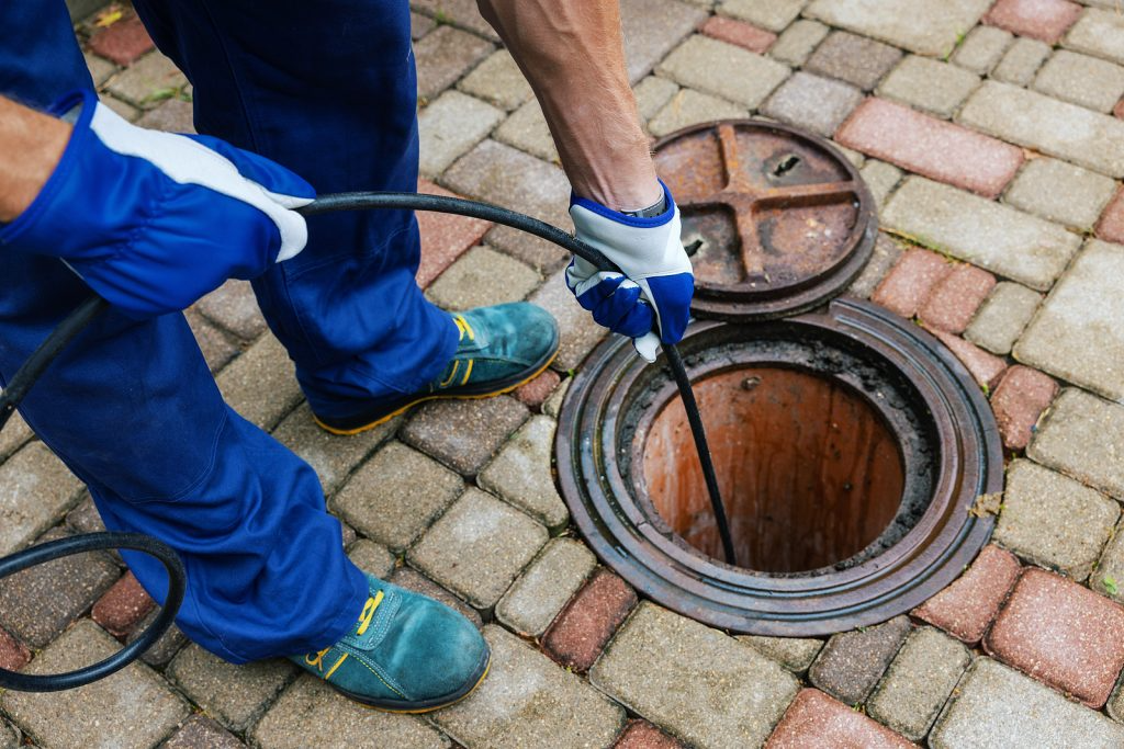 Plumber cleaning an outdoor drain with a cable.